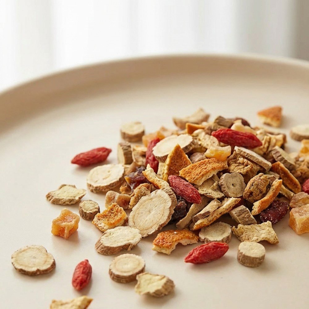 Close-up of CozySlip Ginseng Ginger Goji herbal tea blend on a beige plate, featuring whole ginseng slices, bright red goji berries, dried ginger chunks, and orange peel, showcasing a premium natural wellness tea.