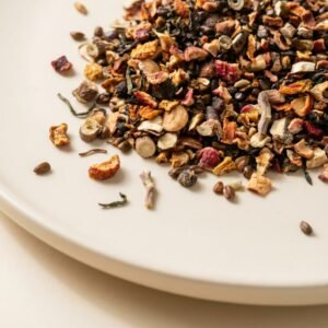 Close-up of CozySlip Han Palace Swallow herbal tea blend on a white plate, featuring a mix of cassia seeds, dried hawthorn, lotus leaf, and citrus peel, showcasing a premium traditional digestive and detox tea.