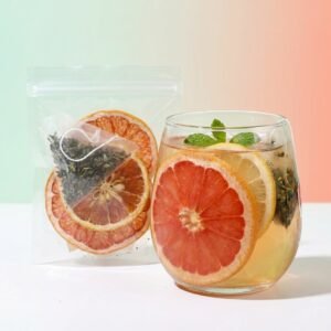 Grapefruit Mint Lift transparent serving beside a chilled grapefruit, lemon and mint tea infusion